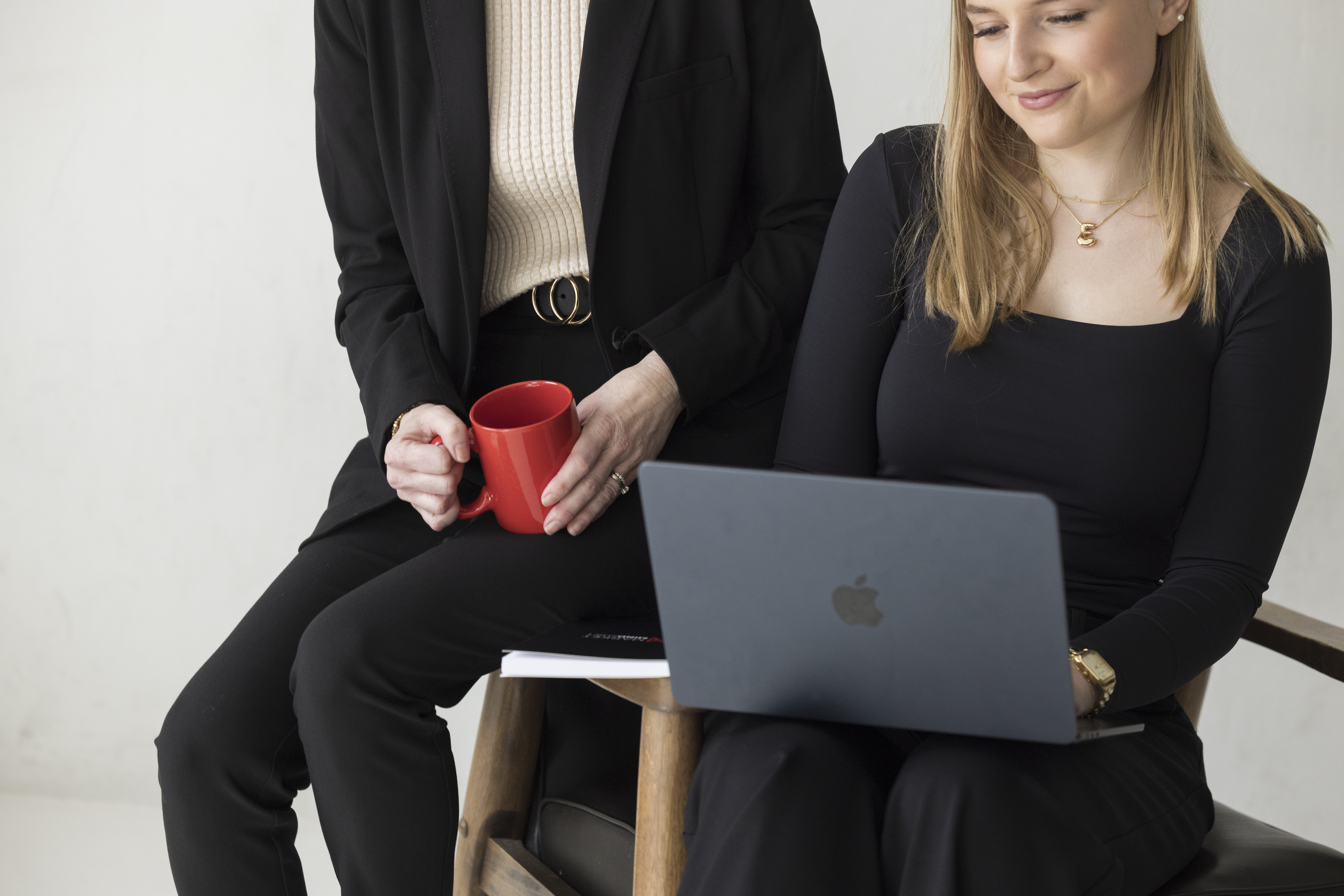 two professionals working on a laptop while drinking from a coffee mug