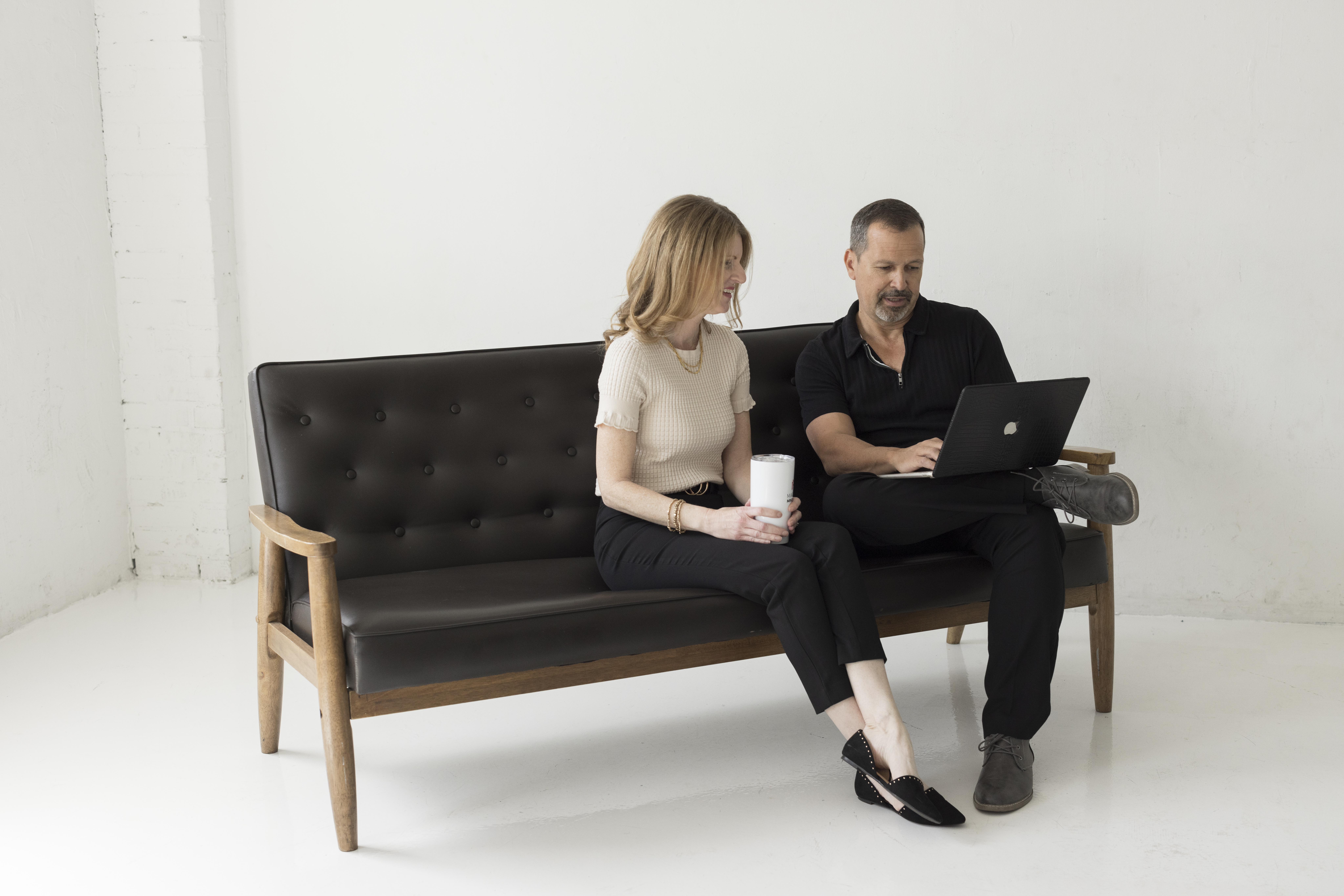 two professionals working at a computer while sitting on a couch